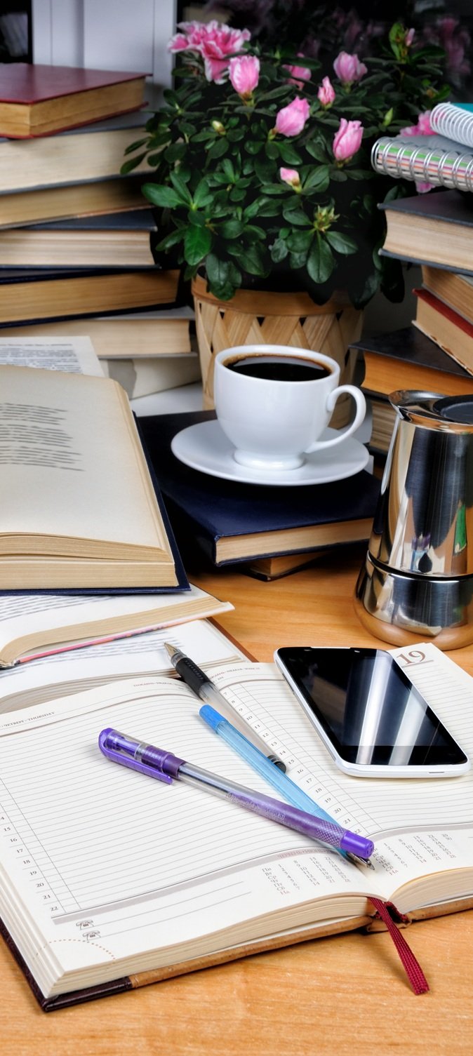 Textbooks, notepad and pen with a cup of black coffee with a coffee pot on a wooden table. Education concept.